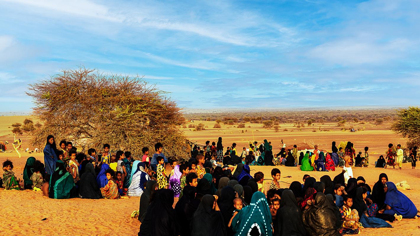 A group of people in brightly coloured clothes sitting in large groups.