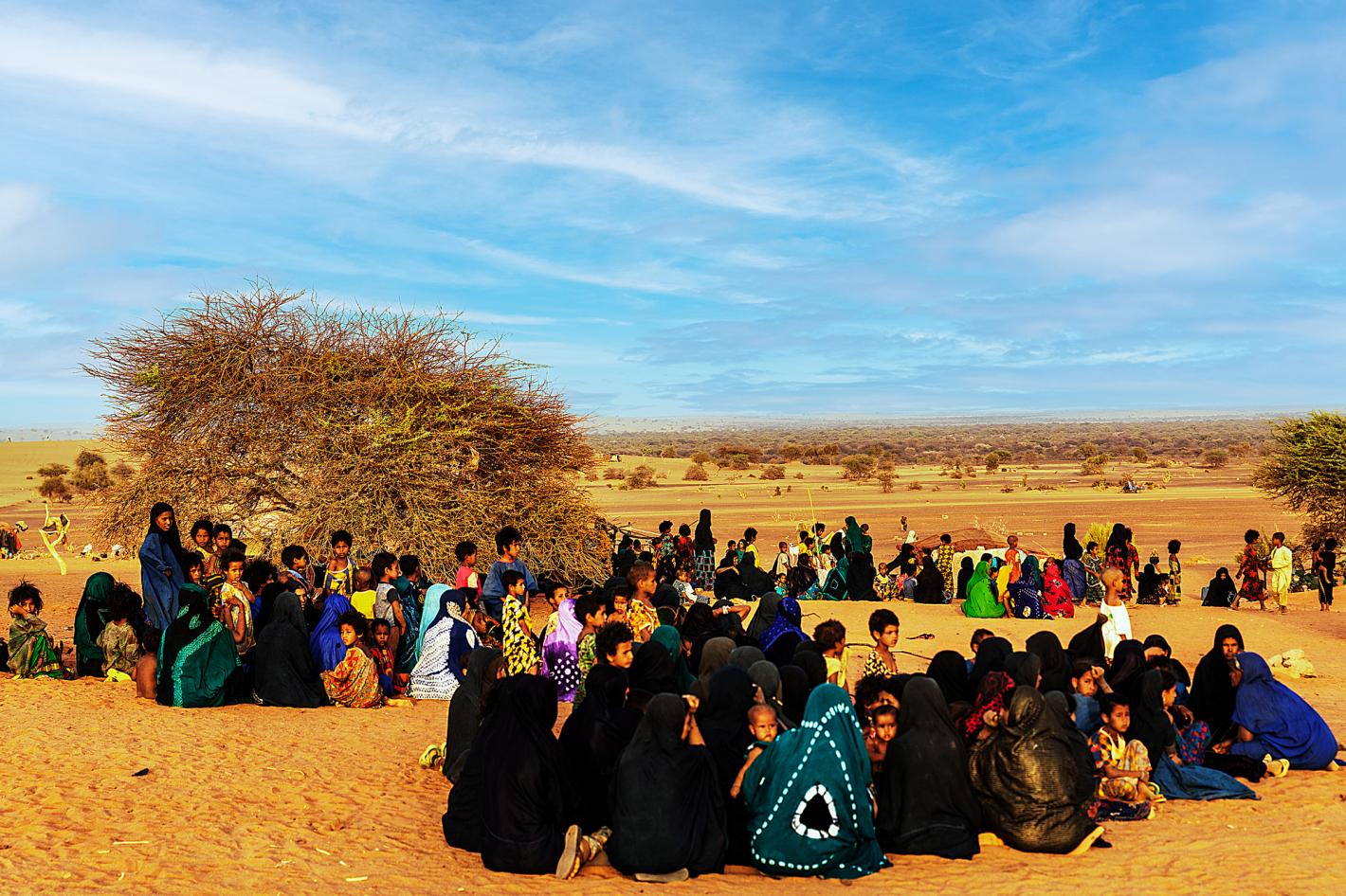 A group of people in brightly coloured clothes sitting in large groups.