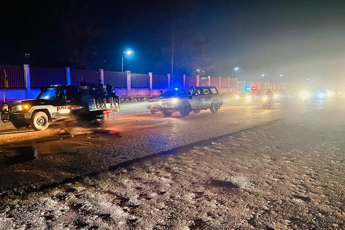 Des véhicules de l'ONU et de la police circulent sur une route de nuit.